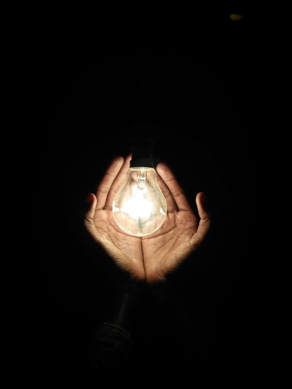 A pair of hands cupping an illuminated lightbulb - Shop C2CLights.com.